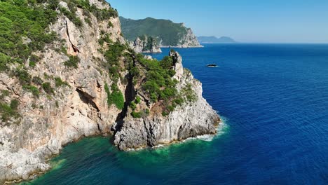 Sunlit-cliffs-and-clear-blue-waters-along-corfu-island's-coastline-in-the-ionian-sea,-aerial-view