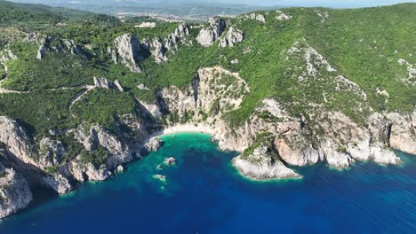 Aerial-shot-of-Giali-Beach-on-Corfu-Island,-Greece-with-clear-turquoise-waters-and-rugged-cliffs,-sunny-day
