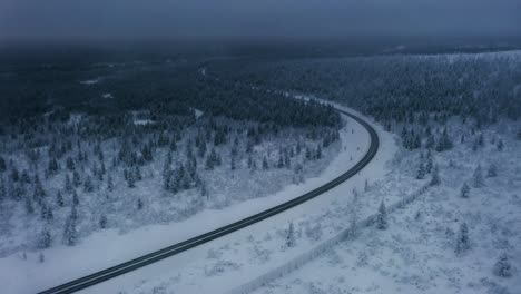 Aerial-view-flying-along-the-road-to-Inari,-foggy-winter-day-in-Lapland