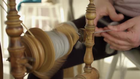 Woman-uses-antique-Nordic-spinning-wheel-to-turn-grey-wool-into-yarn