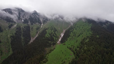 Aerial-shot-of-cloud-kissed-Piatra-Craiului-Mountains-with-lush-green-slopes