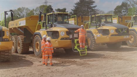 A-team-of-construction-workers-inspect-a-fleet-of-dump-trucks