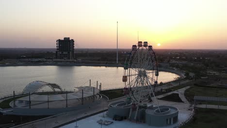 The-sun-is-setting-on-the-side-of-the-lake-and-the-giant-wheel-is-visible