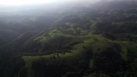 Misty-mountain-range-with-lush-forest-hills-at-dawn,-serene-landscape,-aerial-shot