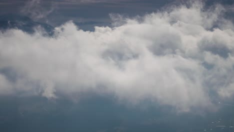 Flug-Durch-Die-Dichten-Weißen-Wolken,-Die-über-Den-Schneebedeckten-Bergen-Und-Einem-Düsteren-Dunklen-Tal-Wirbeln