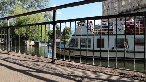 Tourist-boat-going-down-River-Avon-in-Bath,-England-with-tourists-in-slow-motion-stable-video