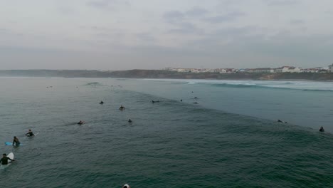 Orbiting-drone-shot-showing-group-of-surfer-in-Atlantic-Ocean-during-cloudy-day