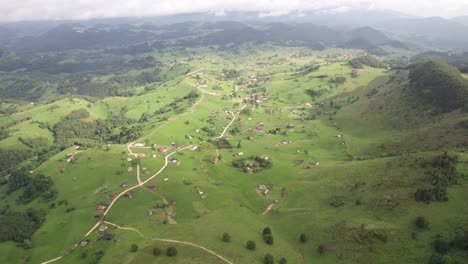 Pueblo-De-Sirnea-En-Rumania-Con-Casas-Dispersas,-Exuberantes-Campos-Verdes-Y-Cielo-Nublado,-Vista-Aérea