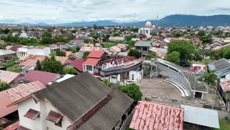 Banda-aceh-with-boats-on-rooftops,-a-reminder-of-the-2004-tsunami,-on-a-cloudy-day,-aerial-view