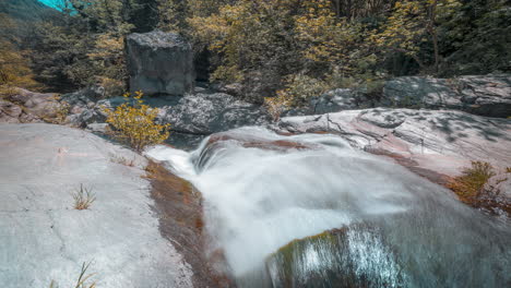 Cascada-En-Un-Bosque-Sereno,-Flujo-Suave-De-Agua-Sobre-Rocas,-Luz-Del-Día,-Timelapse