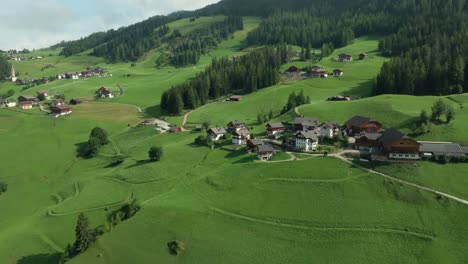 Filmische-Absteigende-Luftaufnahmen-Der-Malerischen-Bauernhäuser-Auf-Den-üppigen-Grünen-Hügeln-Des-Dorfes-La-Val-In-Den-Italienischen-Dolomiten