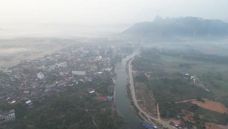 drone-shot-of-river-and-mist-in-Vang-Vieng,-the-adventure-capital-of-Laos