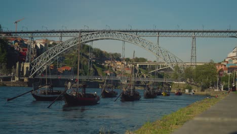 Puente-Ponte-Dom-Luis-En-El-Fondo-Con-Barcos-Locales-En-Primer-Plano-Meciéndose-En-Las-Olas-Y-El-Viento-En-Un-Día-Soleado-Con-Cielos-Azules