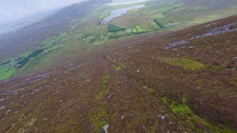 Drone-flying-down-a-hill-towards-the-beautiful-landscape-of-Achill-island