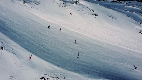 Gente-Esquiando-En-La-Ladera-De-Una-Montaña-Blanca-En-Los-Alpes,-Aérea