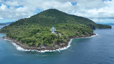 Lush-green-Weh-Island-with-the-iconic-Kilometer-Nol-Monument,-surrounded-by-blue-waters,-aerial-shot