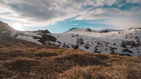 Sunrise-over-snow-covered-hills-with-blue-sky-and-scattered-clouds,-wide-angle-lens