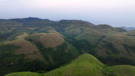 Aerial-View-Of-Lush-Green-Hills-Of-Bukit-Teletubbies-Hill-In-Nusa-Penida,-Bali,-Indonesia-During-Sunset