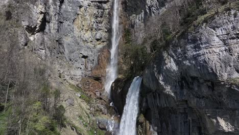 Majestic-Seerenbach-Falls-cascading-down-a-rugged-cliffside-into-Amden,-Walensee,-Switzerland---aerial