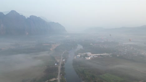aerial-drone-shot-of-misty-valley-in-the-fog-in-Vang-Vieng,-the-adventure-capital-of-Laos
