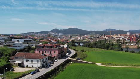 Vibrant-view-of-Barcelinhos,-capturing-Barcelos-across-the-river-with-rural-charm-and-urban-landscape---aerial