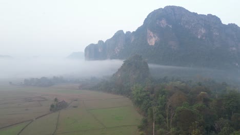 Toma-De-Drones-De-Niebla-Que-Llena-El-Valle-En-Vang-Vieng,-La-Capital-De-Aventuras-De-Laos.