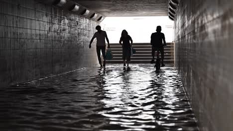 Residents-crossing-a-waterlogged-pedestrian-underpass-after-the-rain-hit-the-UAE-on-May-02,-2024