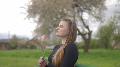 Romantic-beautiful-girl-holds-a-tulip-in-her-hands-and-tries-its-fragrance