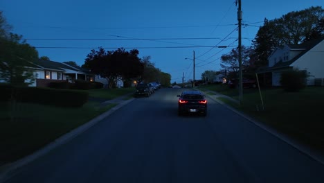 Following-Black-Car-on-street-in-suburb-neighborhood-of-american-town-at-night