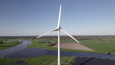 Panorámica-Aérea-Lenta-Que-Muestra-Turbinas-Eólicas-Y-Paneles-Solares-En-Los-Países-Bajos-Con-El-Encuentro-Del-Río-Ijssel-En-El-Fondo.