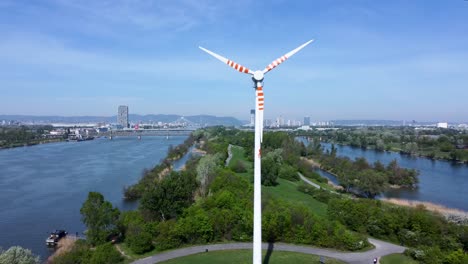 Turbina-Eólica-Girando-En-La-Isla-Del-Danubio-Con-El-Horizonte-Y-El-Río-De-Viena,-Día-Soleado,-Concepto-De-Energía-Renovable,-Vista-Aérea