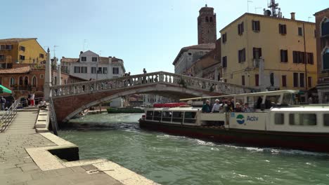 Ein-Mit-Touristen-Gefülltes-Boot-Passiert-Die-Steinbrücke-über-Dem-Canale-Grande-In-Venedig