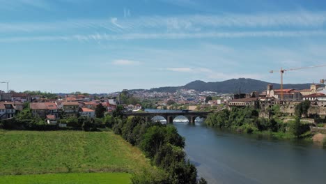 Vista-Aérea-De-Barcelos,-Portugal,-Mostrando-Su-Pintoresco-Río-Y-Su-Puente-Medieval-Bajo-Un-Cielo-Despejado.