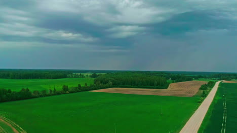 Lebendige-Grüne-Felder-Unter-Einem-Stürmischen-Himmel,-Die-Die-Kontraste-Der-Natur-Hervorheben,-Luftaufnahme