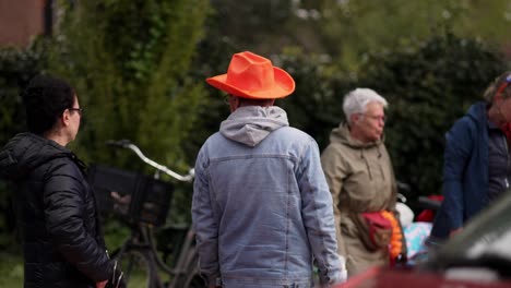 Adult-man-with-orange-cowboy-hat-and-blue-denim-jacket-walking-on-street