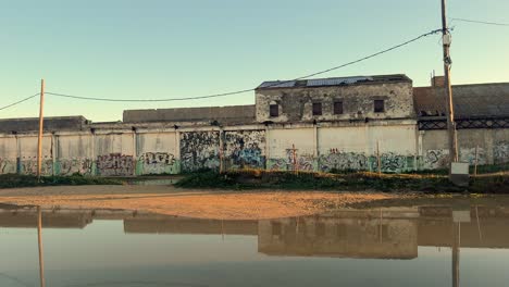 Toma-De-Seguimiento-A-Lo-Largo-De-Una-Pared-Decorada-Con-Murales-Que-Cruzan-Un-Canal.