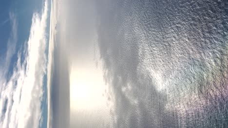 Vista-Aérea-Del-Cielo-Azul-Y-El-Mar,-Clima-Despejado,-Ondas-De-Agua-Del-Sol-Brillante,-Vertical