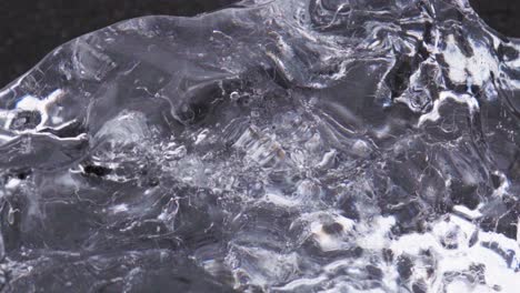 Close-up-details-of-a-chunk-of-ice-on-a-black-sand-beach-in-Iceland--Slow-motion