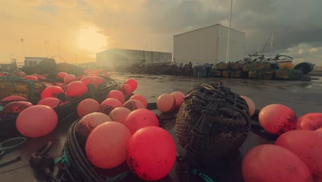 Cheerful-red-buoys-adorn-the-quays-of-a-picturesque-Spanish-fishing-village,-securely-fastened-to-the-coastal-jetty,-offering-a-peek-into-the-allure-of-this-snug-harbor-and-its-fishing-populace