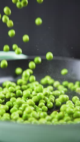 Vertical-shot-of-Green-peas-falling-in-slow-motion-into-a-sizzling-hot-frying-pan