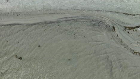 Luftaufnahme-Von-Oben-Auf-Einen-Verschneiten-Strand-Neben-Einem-Meer