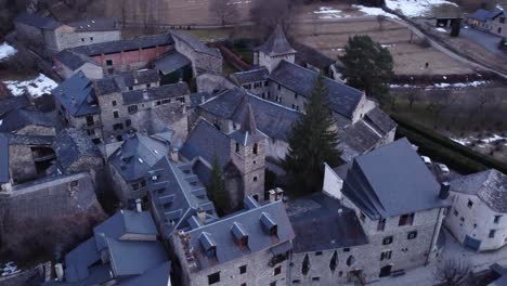 Aerial-of-Anciles,-showcasing-the-rustic-charm-of-an-old-town-church-and-stone-houses-nestled-in-the-Aragonese-Pyrenees,-Spain