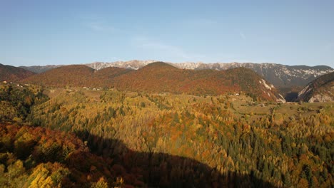 Magura-village-in-autumn-with-vibrant-fall-foliage-and-mountains,-aerial-view