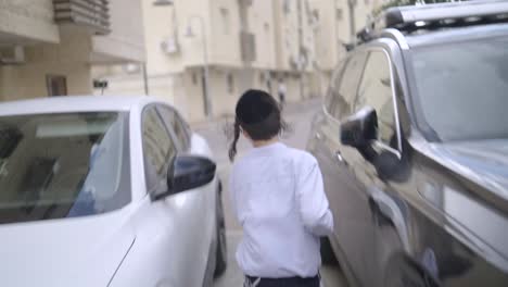 orthodox-jewish-boy-runing-in-the-street-in-isreal,-back-view