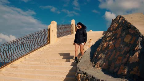Asiatic-tourist-walking-downstairs-on-Cleopatra-Beach-in-Marsa-Matrouh,-Egypt