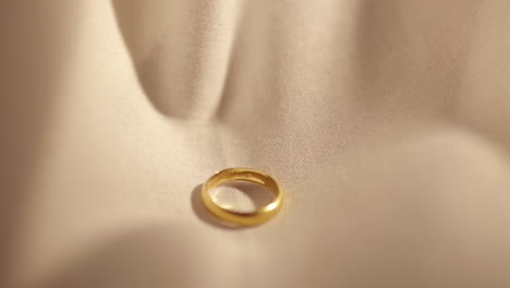 Wedding-Gold-Rings-dropped-on-white-cloth-background
