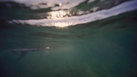 Surfer-Warten-An-Der-Meeresoberfläche,-Während-Sonnenstrahlen-Im-Wasser-Funkeln