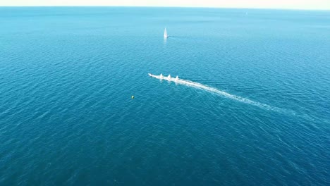 Motorboat-tows-sailboats-on-calm-clear-blue-sea