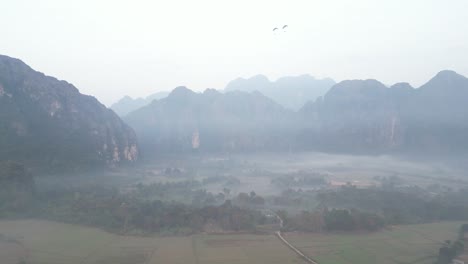 drone-shot-of-fog-during-misty-morning-in-Vang-Vieng,-the-adventure-capital-of-Laos