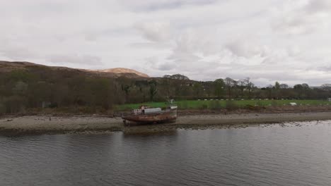 Aerial-closing-shot-of-tourists-walking-around-the-Corpach-Shipwreck